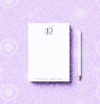 Notebook and pencil on a purple floral patterned background