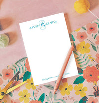 Notepad with personalized name on a floral surface with stationery items