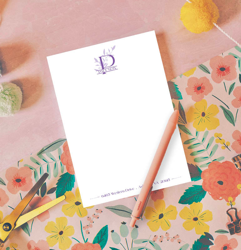 Notebook with floral design on cover, pen, and address card on a floral-patterned surface