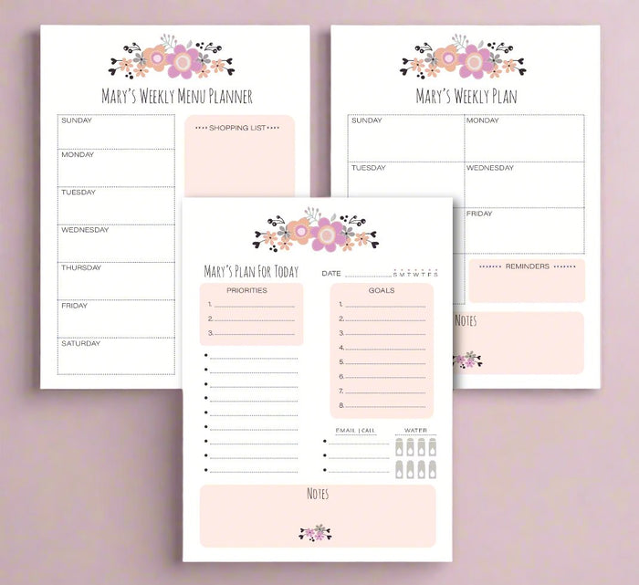 Three planner note pads laid out flat with floral designs on the cover, labeled for daily, weekly, and monthly planning.